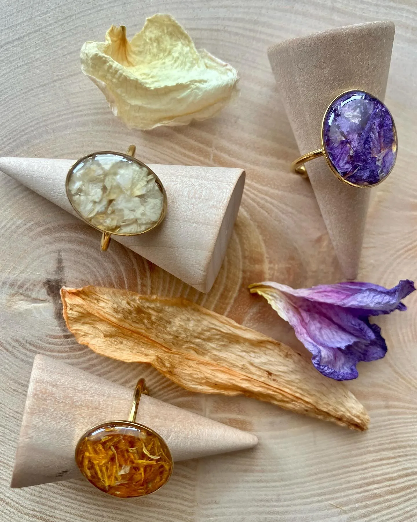 Tres anillos ovalados morado, blanco y ámbar sobre conos de madera