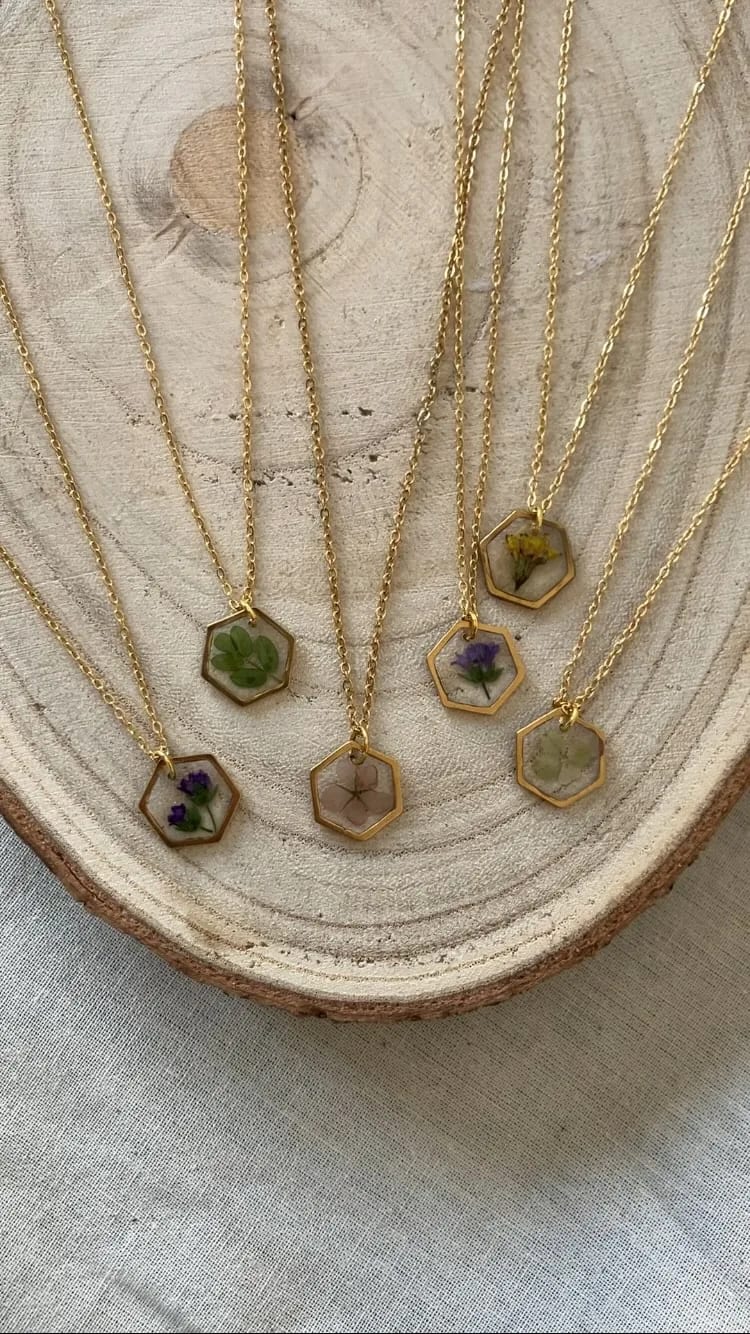 Seis colgantes hexagonales dorados con flores distintas sobre una rodaja de madera