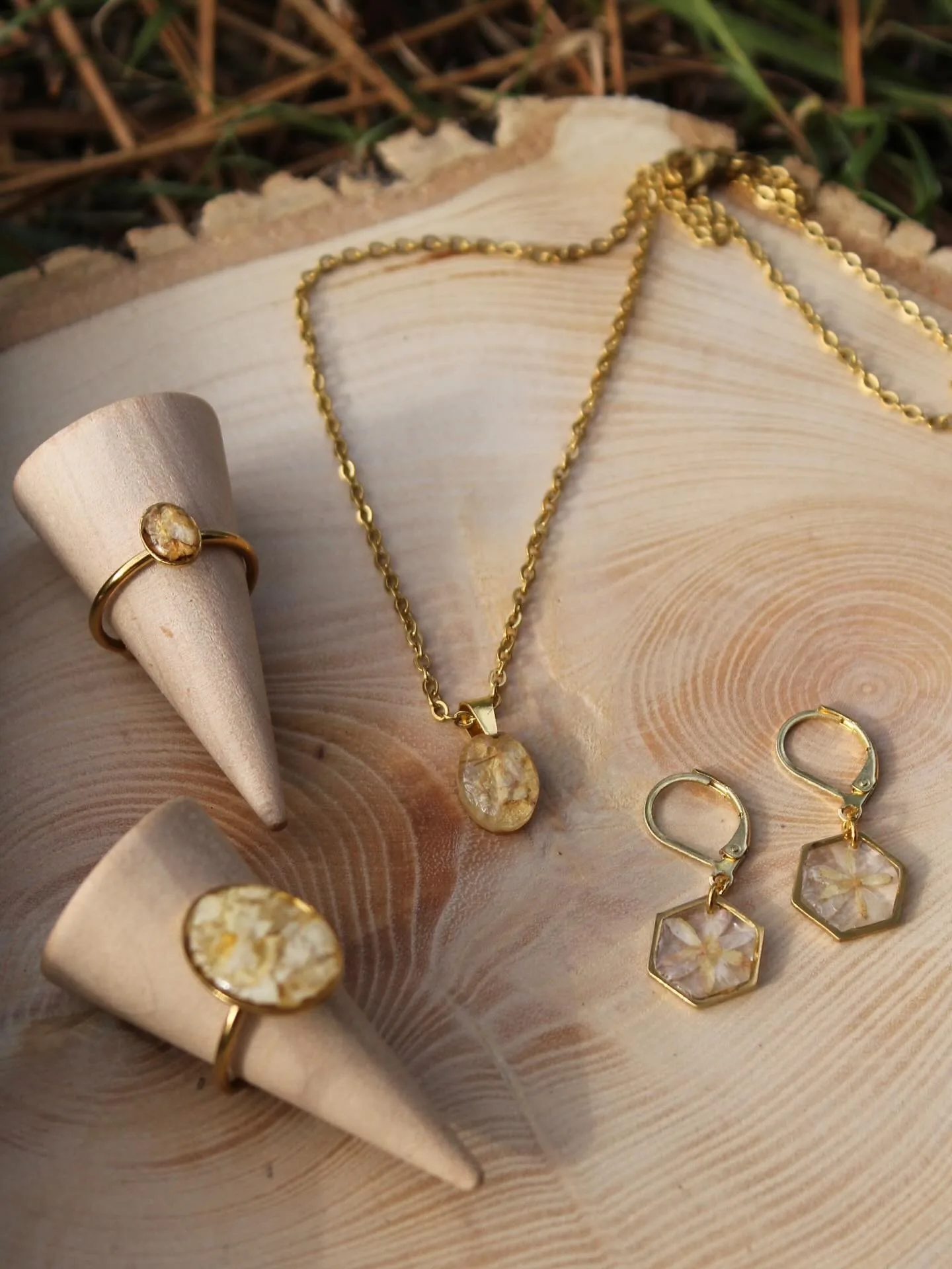 Colgante, pendientes y anillo con pétalos claros sobre conos de madera