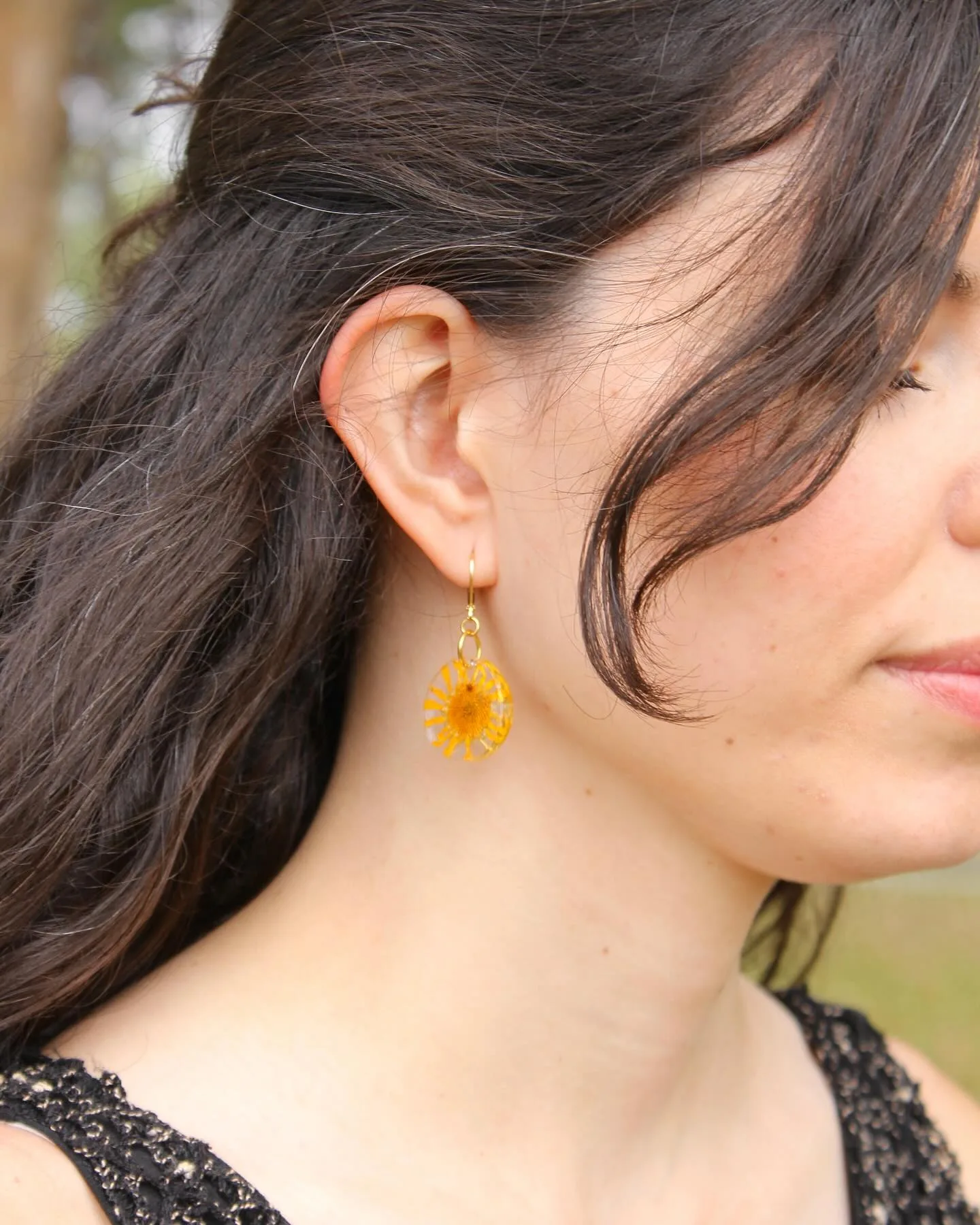 Pendiente pequeño con una margarita amarilla puesto en la oreja