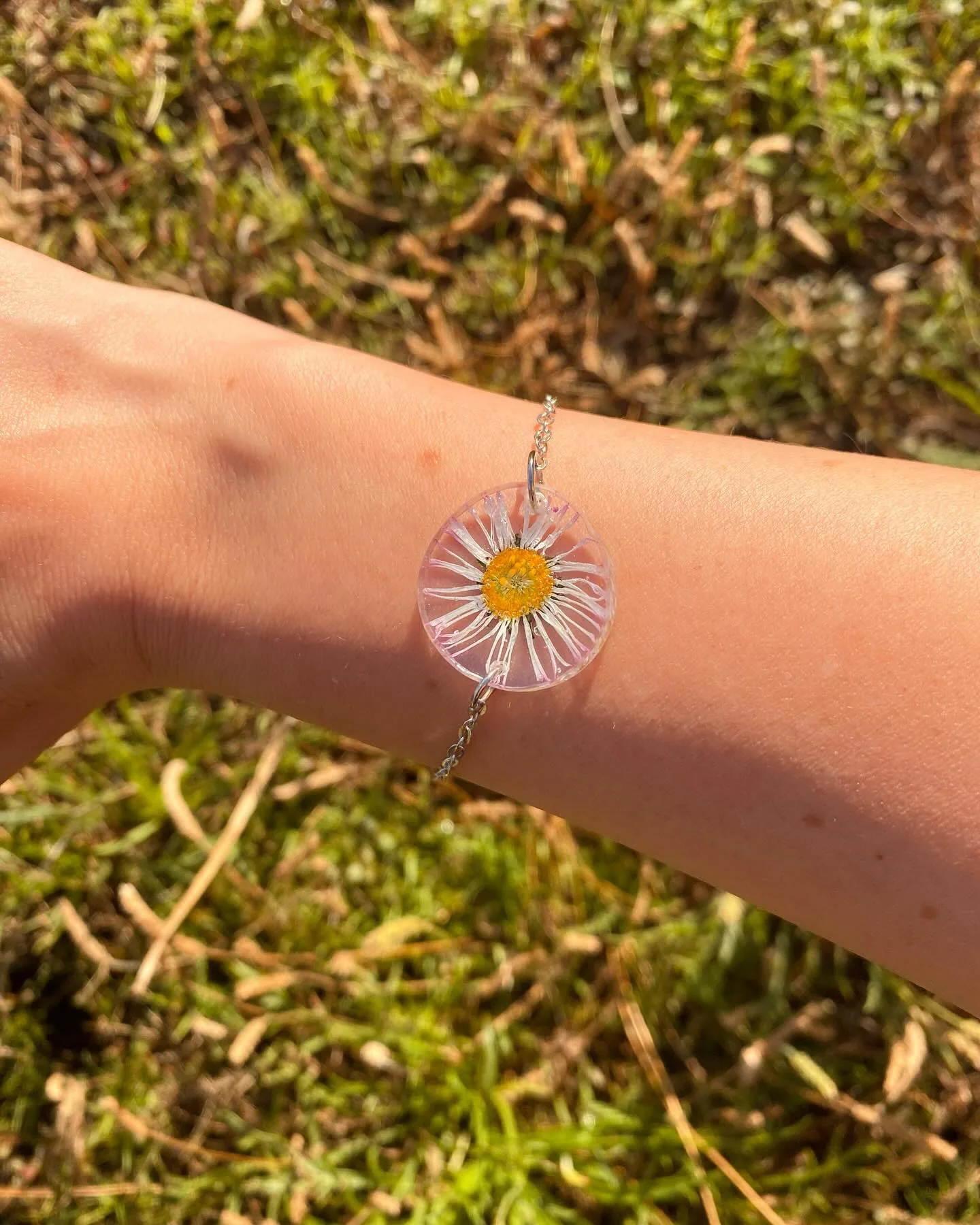 Pulsera con una margarita blanca en la muñeca sobre musgo
