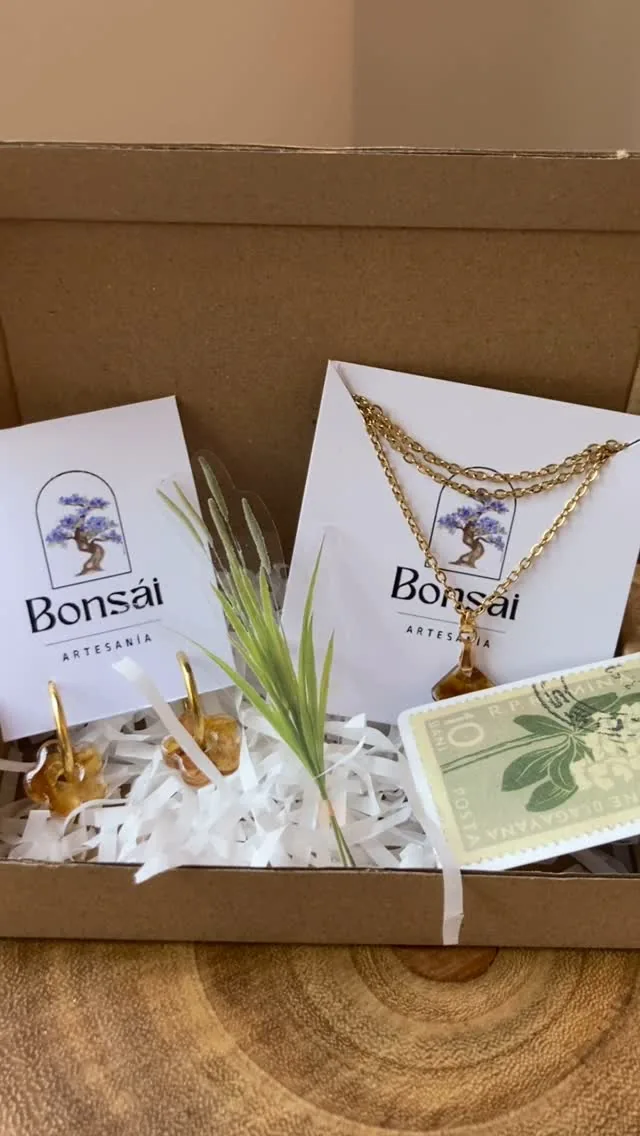 Caja de envío con pendientes y un colgante ámbar en sus tarjetas, junto a un sello antiguo