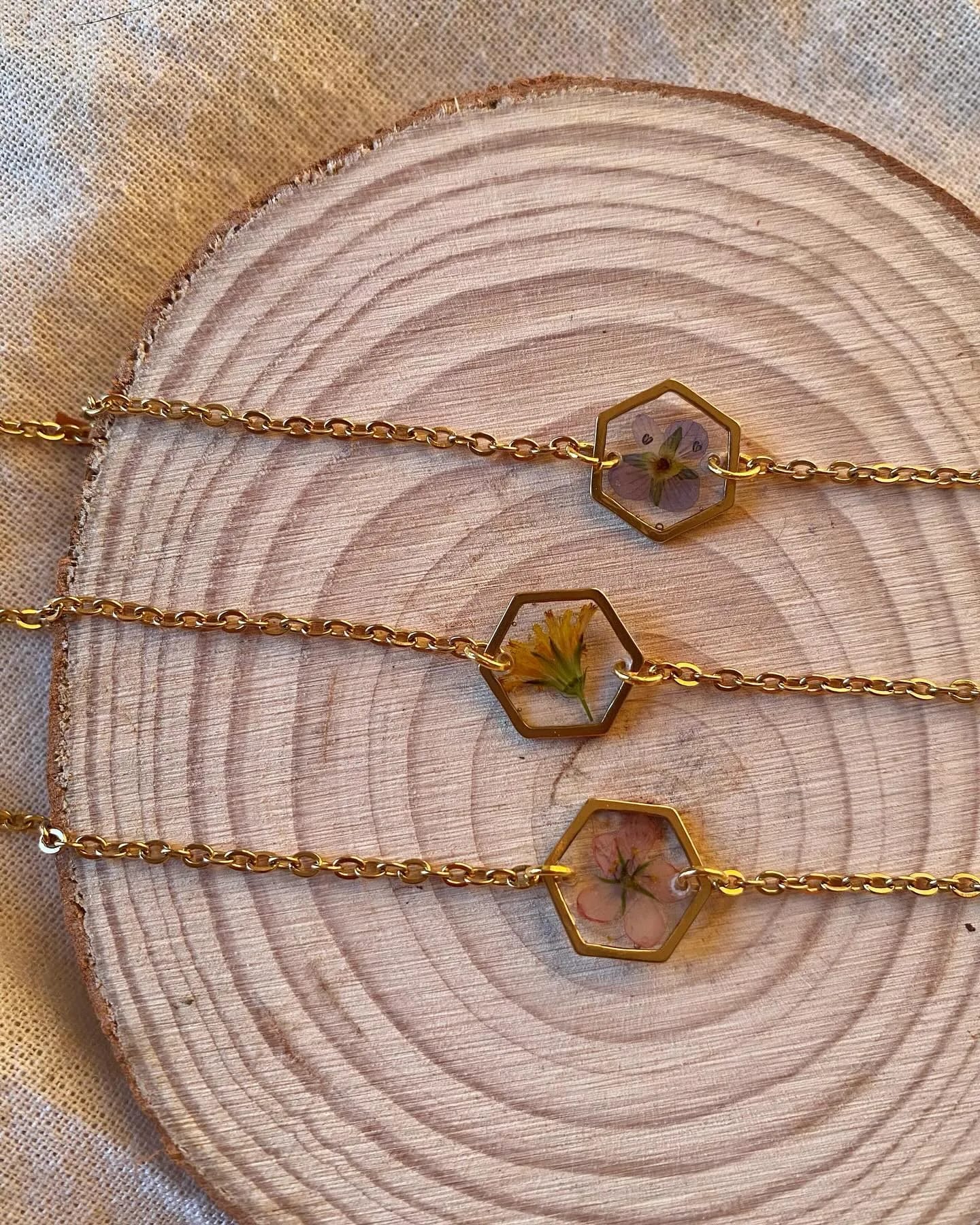 Tres pulseras de cadena dorada con hexágonos de resina y flores